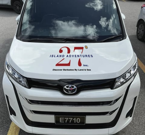 White Toyota van with Island Adventures branding and logo on the hood, parked front view